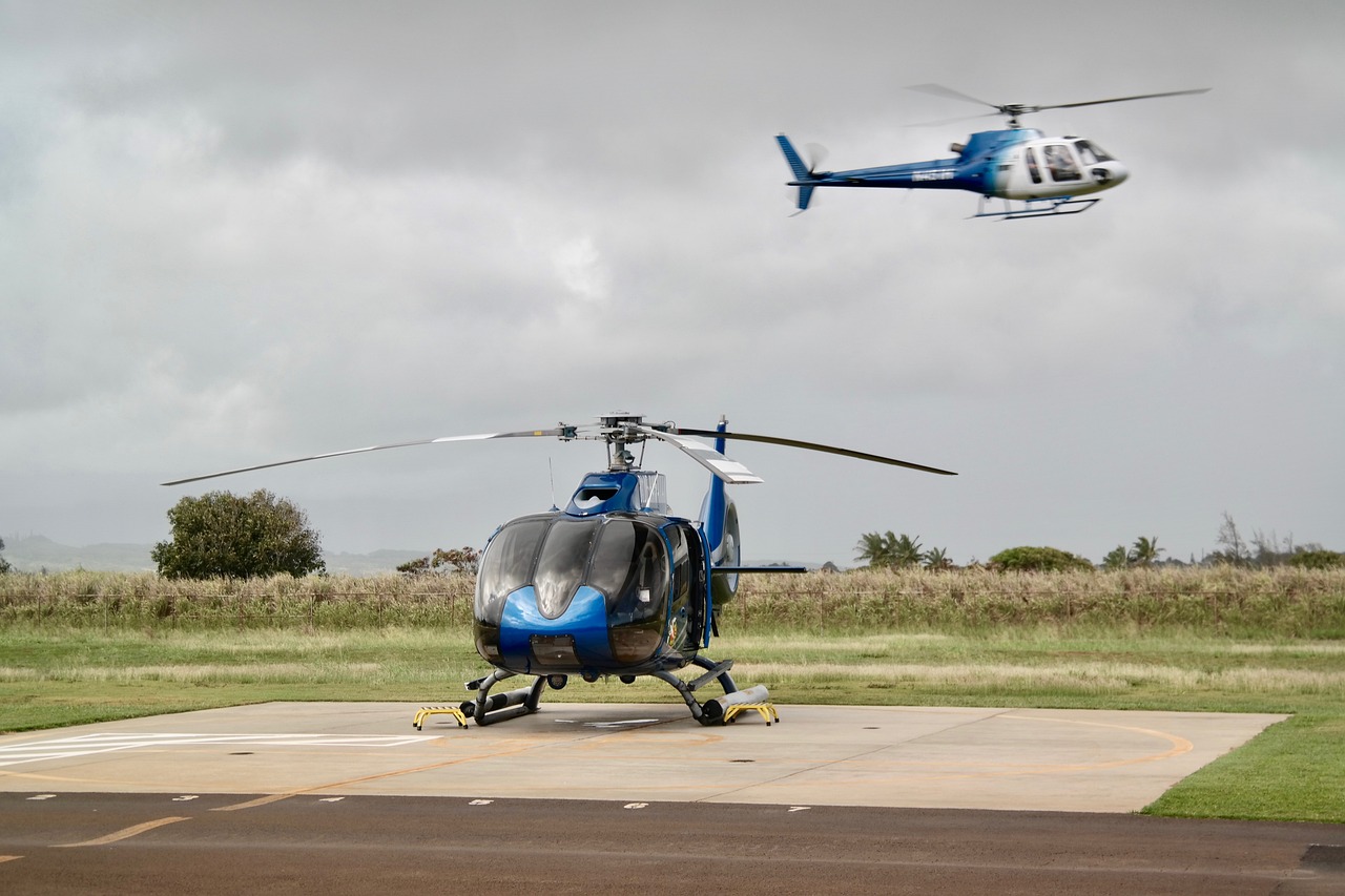 Two helicopters, one in the air, ready for helicopter tours